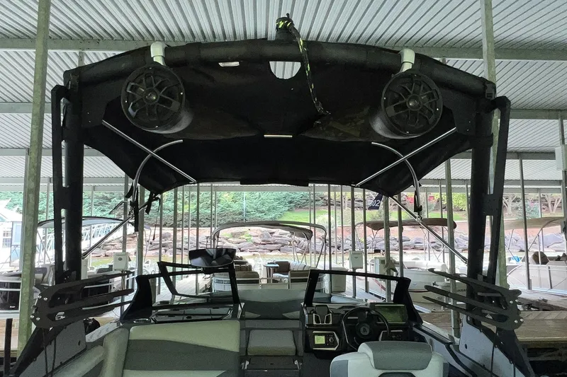 Slide: The Image of 2023 Axis A225 boat interior with speakers and dashboard under a covered dock. - 27
