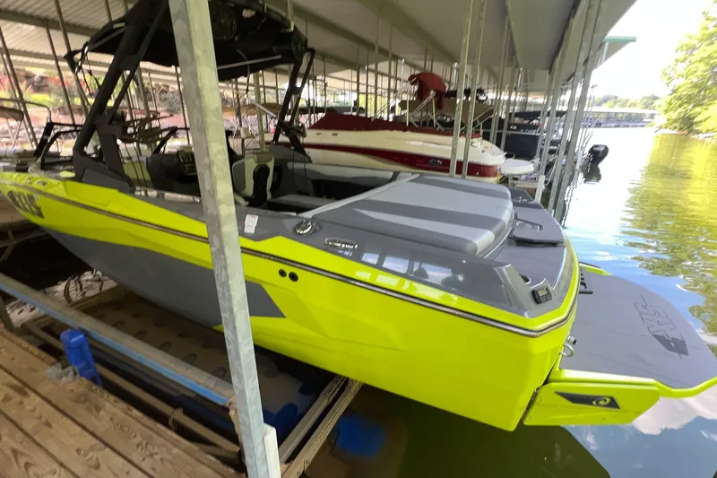 Slide: The Image of A bright yellow 2023 Axis A225 boat is docked under a covered area by the water. - 3