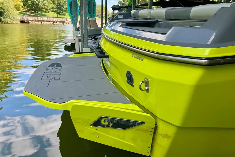 Slide: The Image of 2023 Axis A225 boat with vibrant yellow exterior, docked on a calm lake. - 5