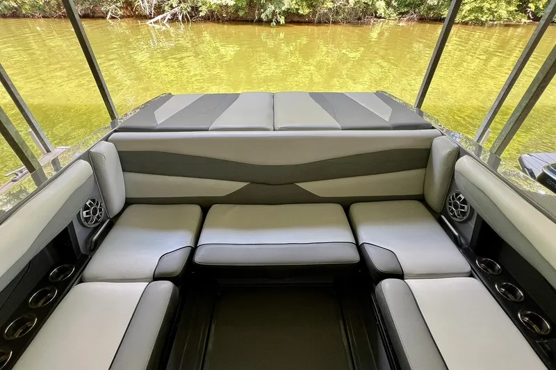 Slide: The Image of 2023 Axis A225 boat interior with cushioned seating and cup holders by the water. - 10
