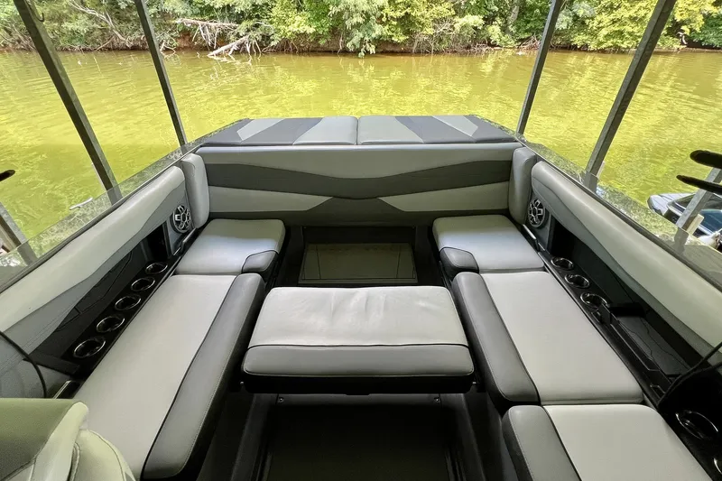 Slide: The Image of 2023 Axis A225 boat interior with cushioned seating and cup holders by a lake. - 13