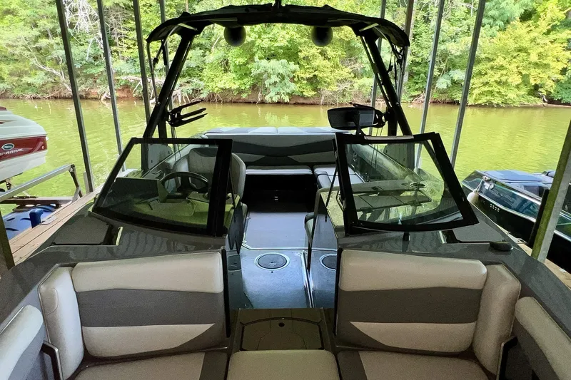 Slide: The Image of 2023 Axis A225 boat interior with seating, docked by a lush green shoreline. - 26