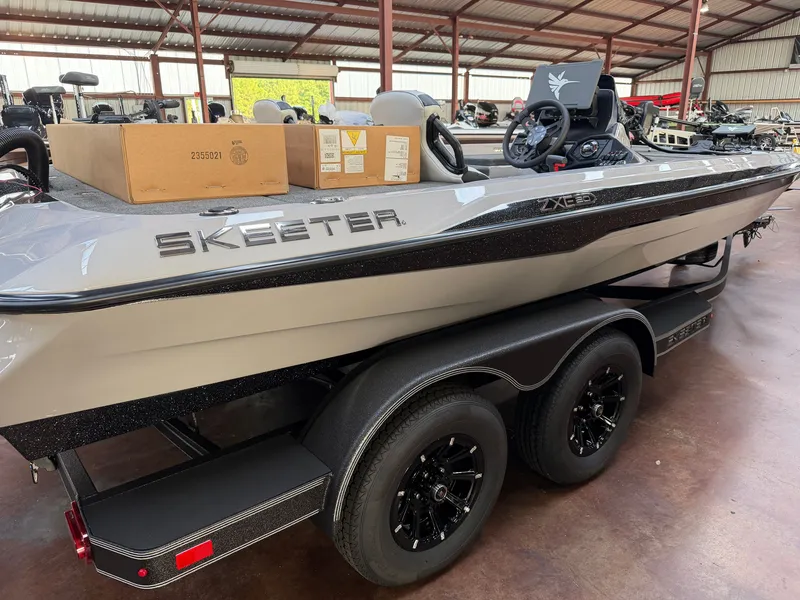 The Image of A gray Skeeter ZXE20 boat from 2027 sits on a trailer in a covered area. - 1