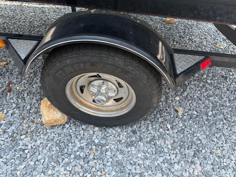 Slide: The Image of A boat trailer with a black fender and a tire on a gravel surface. - 15