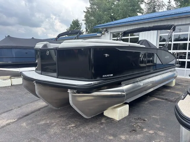 Slide: The Image of A sleek pontoon boat with a black hull and silver pontoons, parked on a paved area. - 3