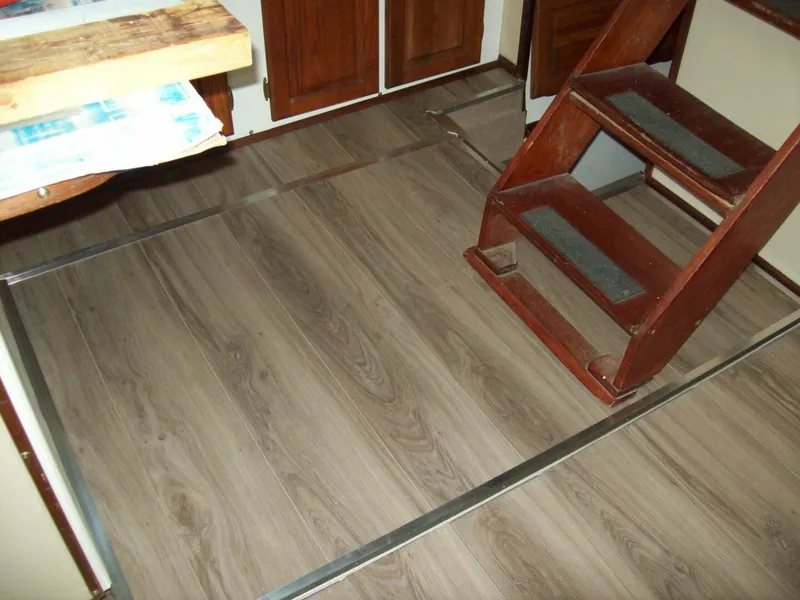 Slide: The Image of Interior of a boat with wooden stairs and flooring, surrounded by cabinets. - 12