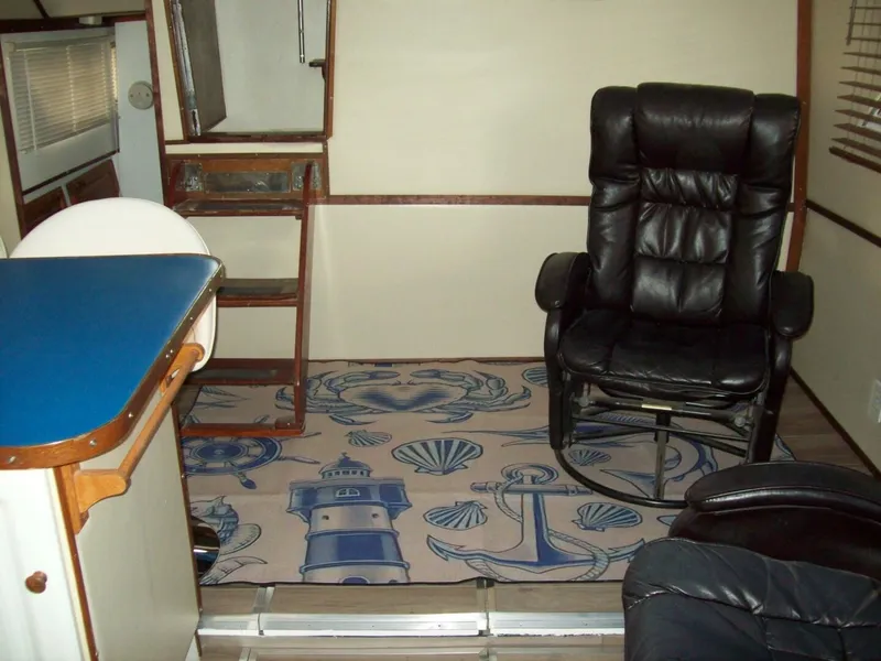 Slide: The Image of The interior of a 1979 Chris-Craft 350 Catalina features a cozy seating area with leather chairs and a nautical-themed rug. - 5
