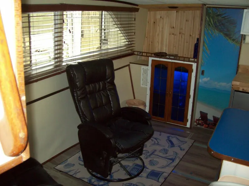 Slide: The Image of The interior of a 1979 Chris-Craft 350 Catalina features a cozy armchair and wooden furnishings. - 7