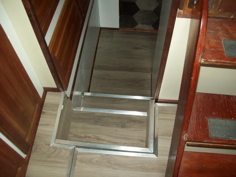 Slide: The Image of Interior of a boat with wooden stairs and laminate flooring. Metal frame surrounds a floor opening. - 11