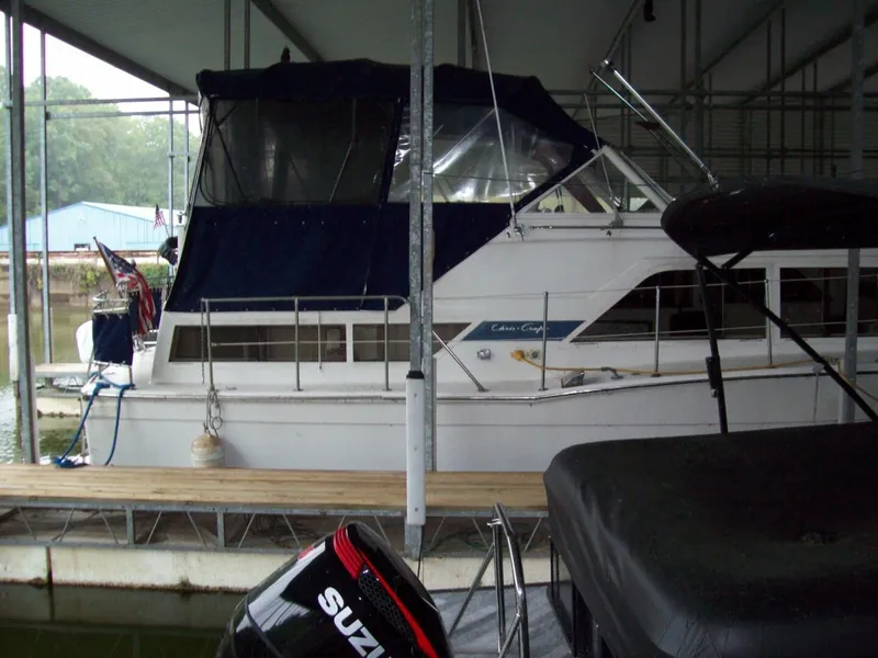 The Image of A 1979 Chris-Craft 350 Catalina docked under a covered area. It features a blue canopy. - 0