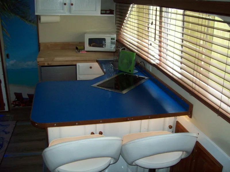 Slide: The Image of The galley of a 1979 Chris-Craft 350 Catalina with a blue countertop and white bar stools. - 4
