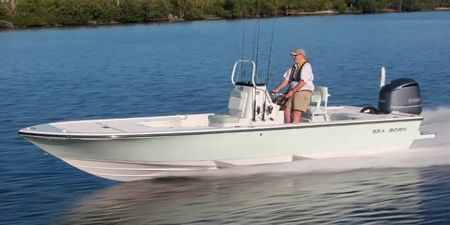 Slide: The Image of A man drives a Sea Born FX25 Bay boat on calm water. - 1