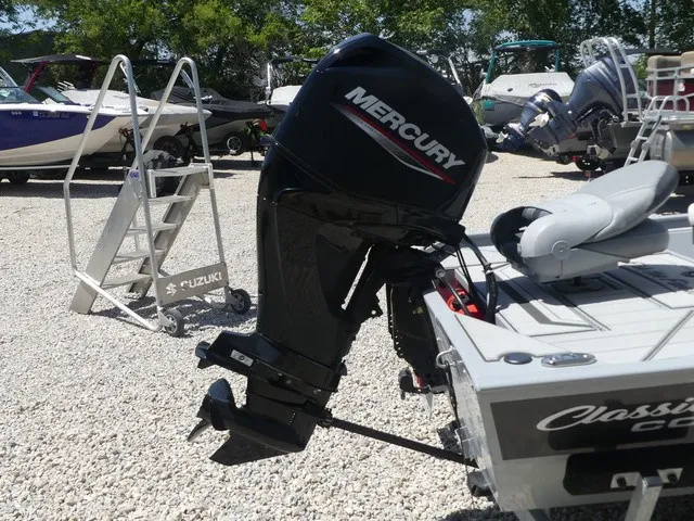 Slide: The Image of A Mercury outboard motor is mounted on a Tracker Bass Tracker Classic CC boat, situated on a gravel lot. - 16