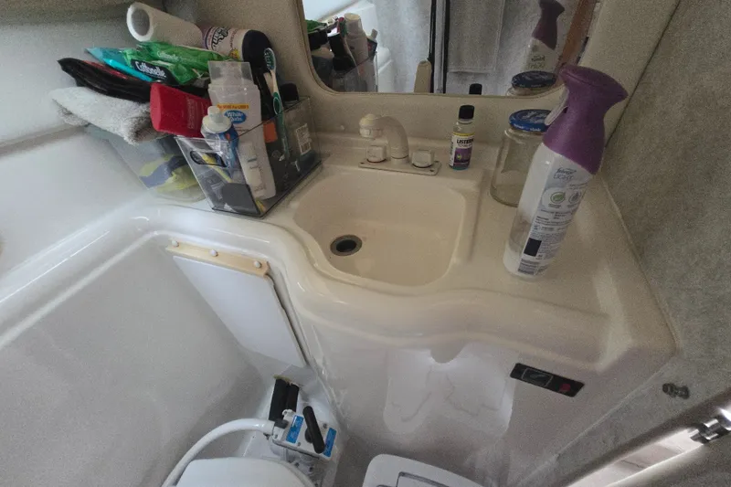 Slide: The Image of Bathroom sink area in a 1998 Bayliner 2655 Ciera boat, with toiletries and cleaning supplies. - 18
