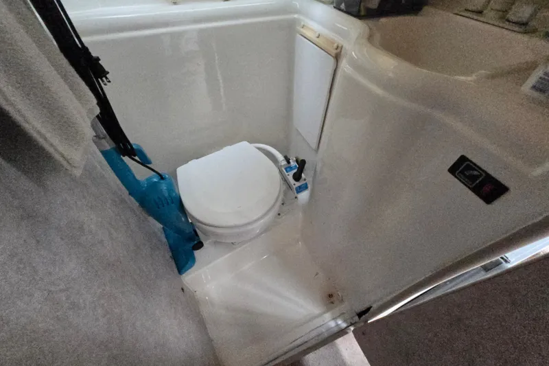 Slide: The Image of 1998 Bayliner 2655 Ciera boat bathroom with compact toilet and cleaning supplies. - 17