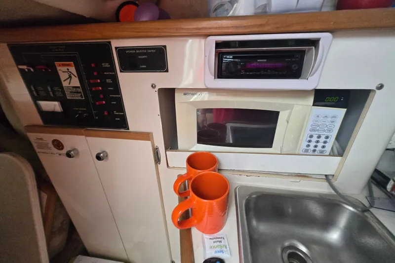 Slide: The Image of 1998 Bayliner 2655 Ciera cabin kitchen with microwave, sink, and control panel. - 19