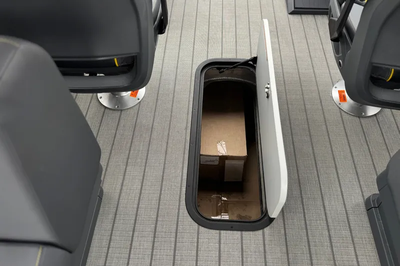 Slide: The Image of Under-seat storage compartment in 2025 Manitou EXPLORE 24 boat, featuring a cardboard box. - 24