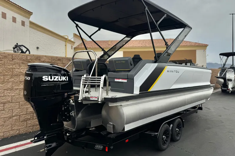Slide: The Image of 2025 Manitou EXPLORE 24 pontoon boat with Suzuki engine, parked outdoors. - 6