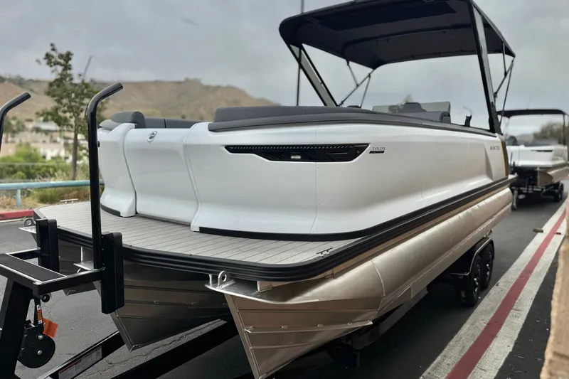 Slide: The Image of 2025 Manitou EXPLORE 24 pontoon boat on trailer, sleek design, outdoor setting. - 3