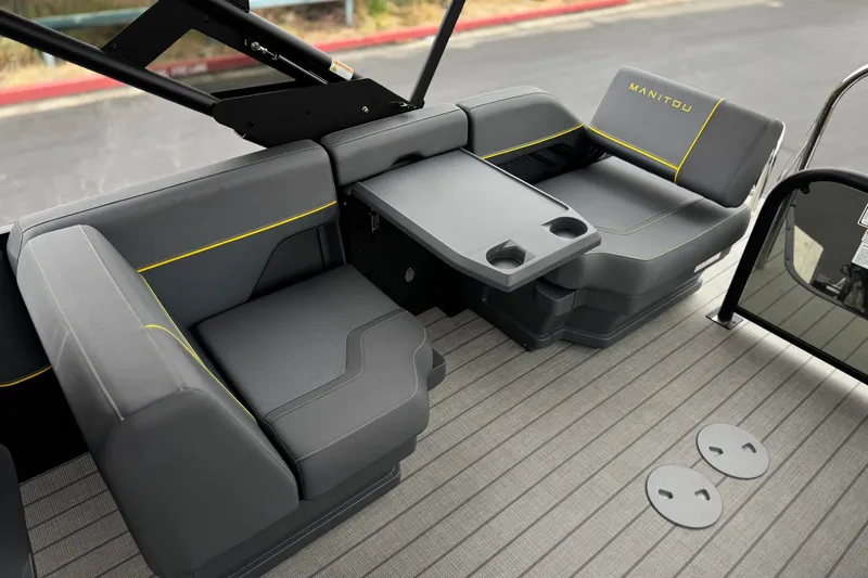 Slide: The Image of 2025 Manitou EXPLORE 24 boat interior with gray seating and foldable table. - 17
