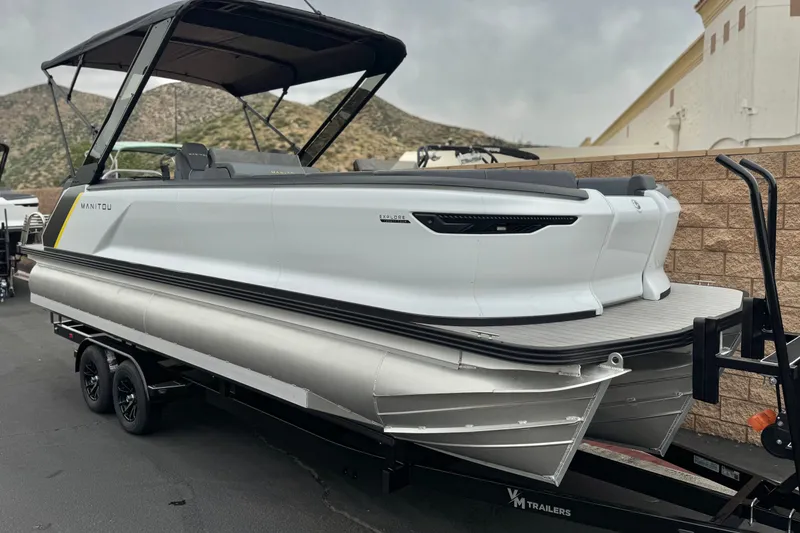 Slide: The Image of 2025 Manitou EXPLORE 24 pontoon boat on trailer, parked outdoors. - 1