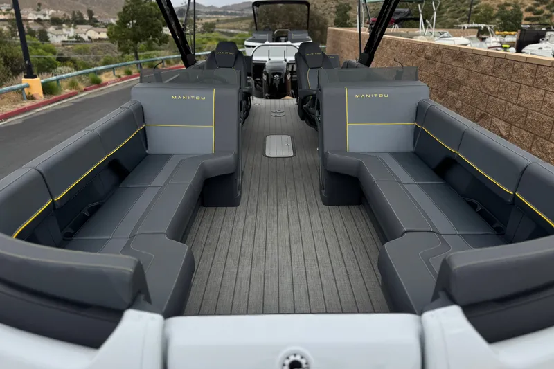 Slide: The Image of 2025 Manitou EXPLORE 24 boat interior with gray seating and yellow accents. - 9