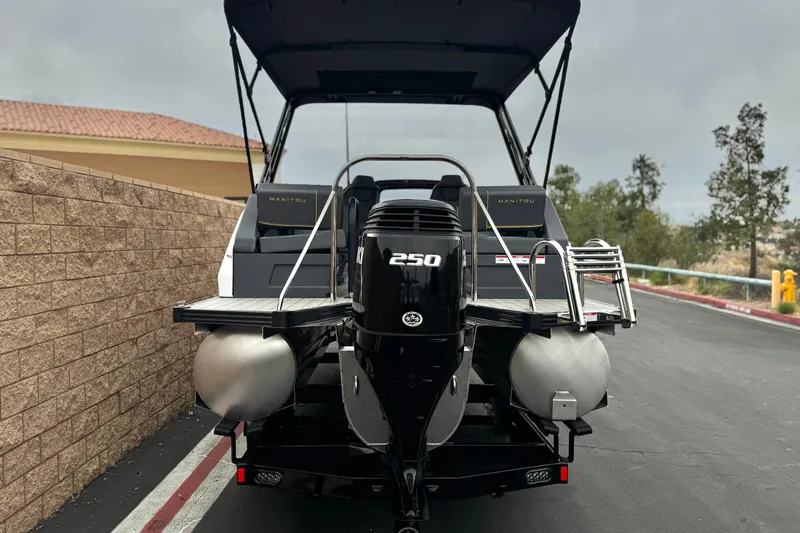 Slide: The Image of 2025 Manitou EXPLORE 24 pontoon boat with powerful 250 HP engine, parked outdoors. - 5