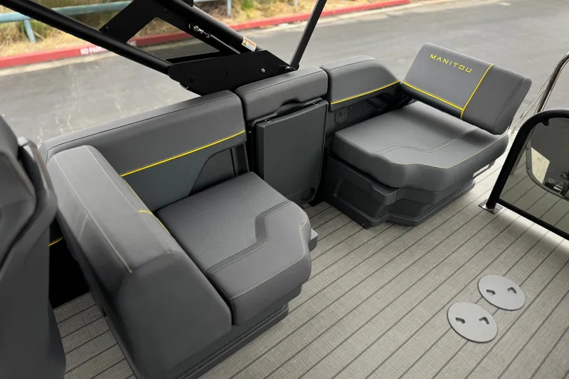 Slide: The Image of 2025 Manitou EXPLORE 24 boat interior with sleek gray seating and yellow accents. - 16