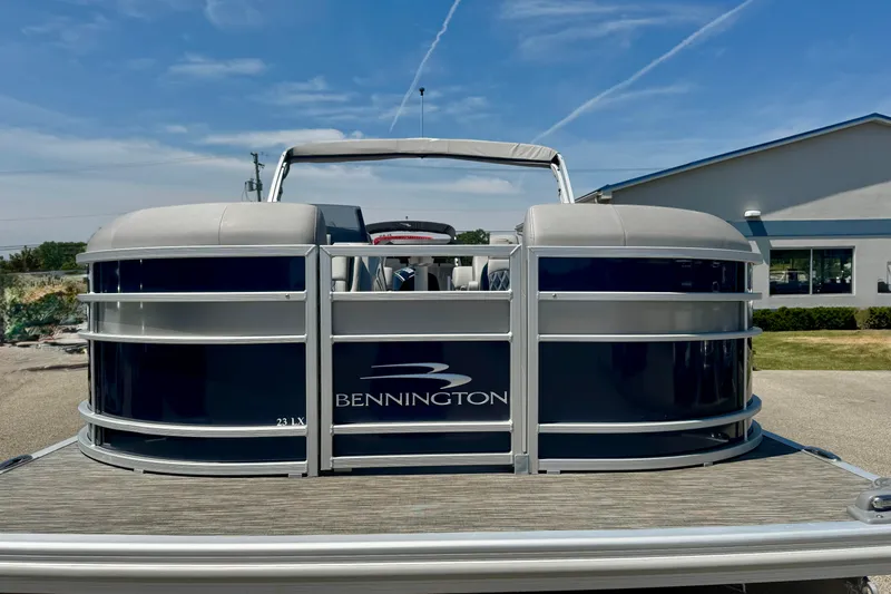 Slide: The Image of 2023 Bennington 23 LX STERN RADIUS pontoon boat, front view under clear blue sky. - 2