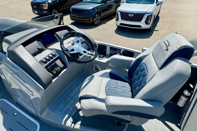 Slide: The Image of 2023 Bennington 23 LX STERN RADIUS boat interior with luxury captain's chair and steering console. - 7