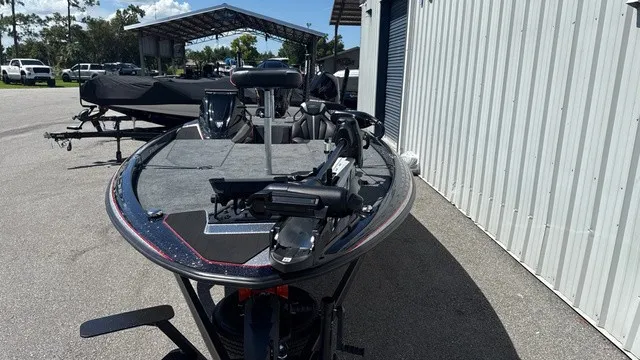 Slide: The Image of A modern bass boat with a gray deck and black hull is parked next to a building. - 8