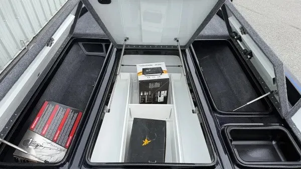 Slide: The Image of The image shows the storage compartments of a 2027 Phoenix 921 Elite X boat with open hatches. - 12