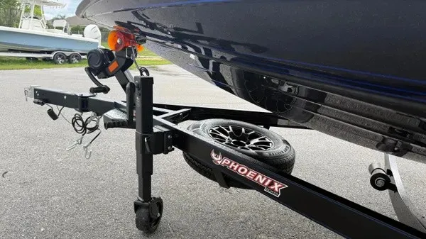 Slide: The Image of A Phoenix 921 Elite X boat on a trailer, featuring a spare tire and hitch. - 9