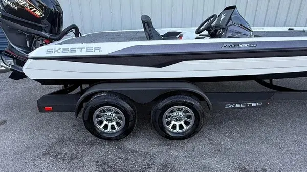 Slide: The Image of A white Skeeter ZXR21 SE boat on a dual-axle trailer with shiny rims. - 4