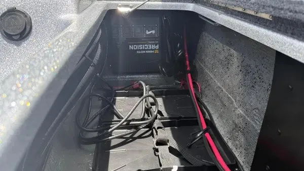Slide: The Image of An open storage compartment with cables and a battery inside a boat. - 26