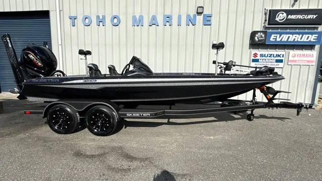 The Image of A black Skeeter ZXE20 boat from 2027 sits on a trailer in front of a building with various brand logos. - 1