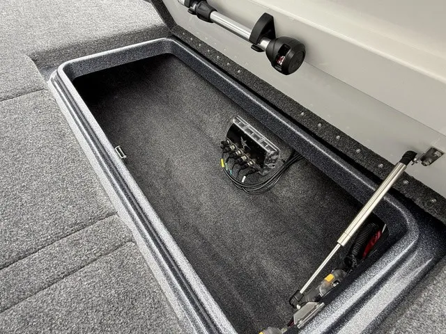 Slide: The Image of Storage compartment in Phoenix 921 Elite X II boat, featuring gray carpet and gas struts. - 21