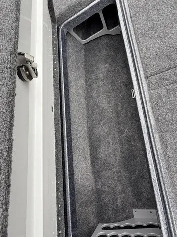 Slide: The Image of Interior view of a boat storage compartment with gray carpeting and black compartments. - 24