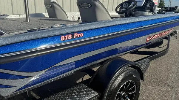 Slide: The Image of A blue Phoenix 818 Pro boat with a black trailer, parked on a lot. - 4