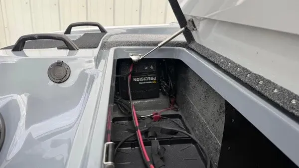 Slide: The Image of An open storage compartment on a 2027 Phoenix 920 Elite X boat reveals batteries and cables. - 22