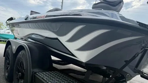Slide: The Image of A gray boat with white accents on a trailer, under a cloudy sky. - 7