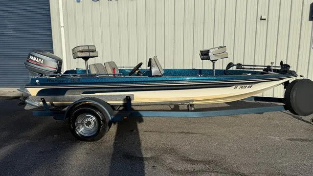 The Image of A 1985 Ranger 330-v boat with a Yamaha outboard motor, parked on a trailer by a building. - 1