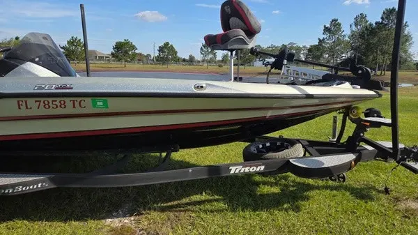 Slide: The Image of A 2021 Triton 20 TrX boat on a trailer, parked on grass. - 3