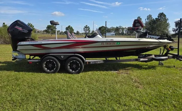 The Image of A 2021 Triton 20 TrX boat on a trailer, parked on grass, ready for the water. - 1
