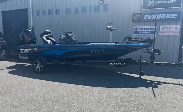 The Image of A blue Nitro Z18 boat on a trailer in front of a building with various brand logos. - 1