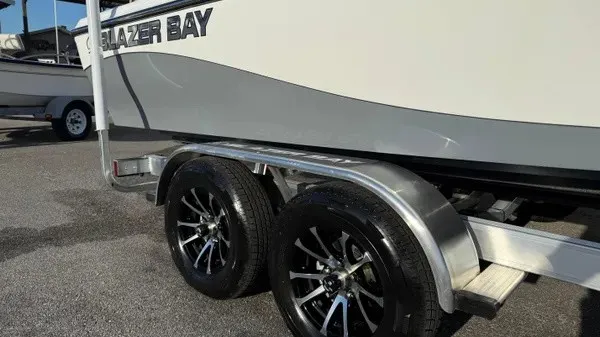 Slide: The Image of A Blazer PureBay 2200 boat on a trailer with shiny black wheels. - 2