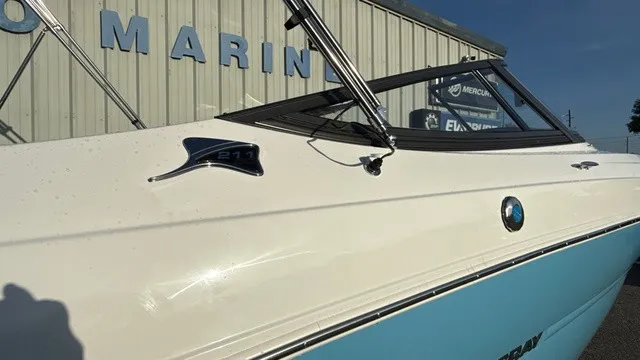 Slide: The Image of A 2027 Stingray 211 DC boat with a blue and white hull, parked in front of a building. - 3