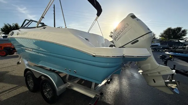 Slide: The Image of A blue and white 2027 Stingray 211 DC on a trailer. A Suzuki outboard motor is attached. - 5