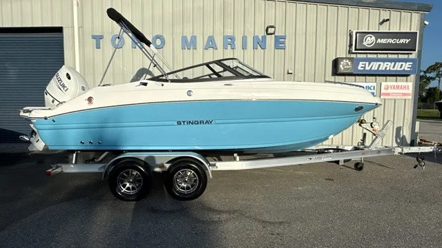 The Image of A 2027 Stingray 211 DC boat on a trailer in front of a building. - 1