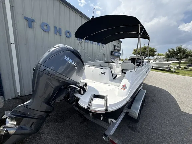 Slide: The Image of A white 2027 Stingray 212 SC boat with a Yamaha outboard motor, parked in front of a building. - 3